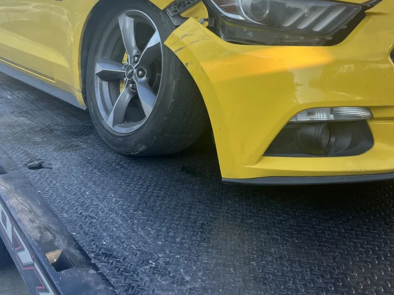 Ford Mustang with front-end damage on a flatbed after an accident in Dallas, TX